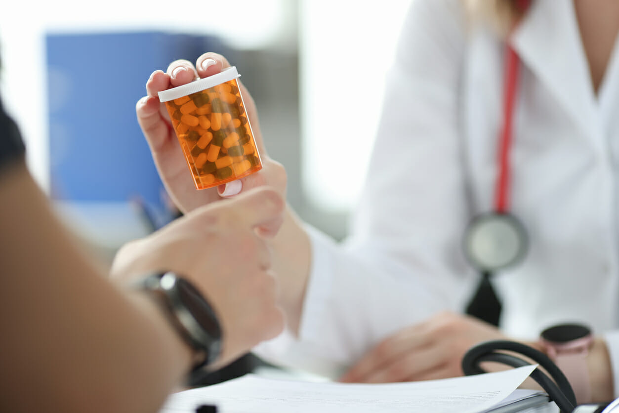 Pharmacy employee in Winter Haven, FL, handing a bottle of medication to a patinet.
