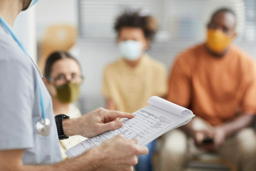 A physician reviewing hi clipboard for the next patient's name at their medical center.