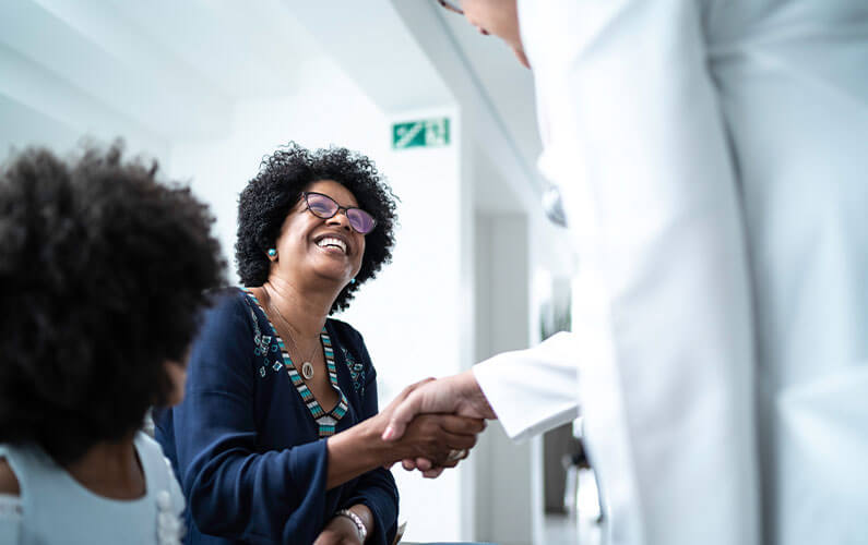 A doctor specializing in concierge healthcare shaking hands with his older female patient.