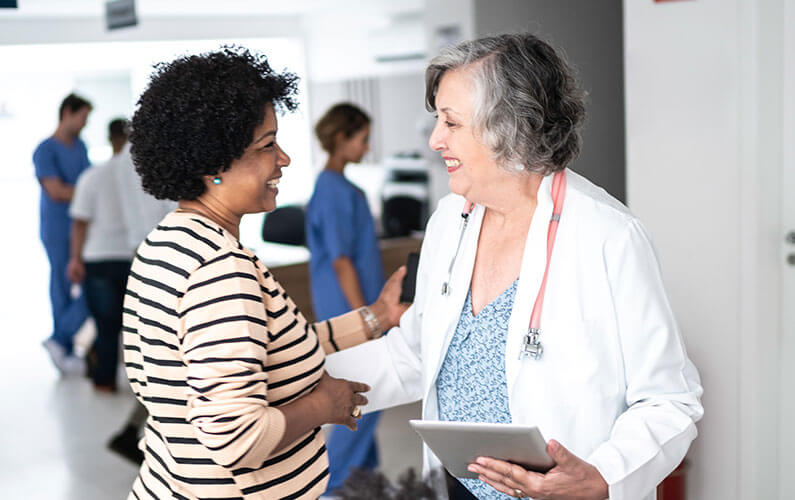A female doctor offering specialty care shaking hands with her older female patient.