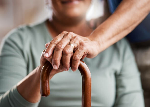 healthcare provider's hand over a senior's hand holding a crane- Medicare for seniors concept
