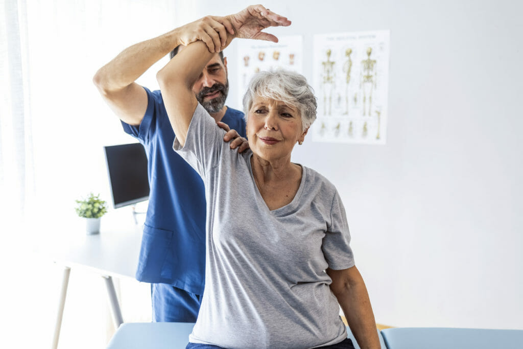 physical therapist helping old woman in exercise