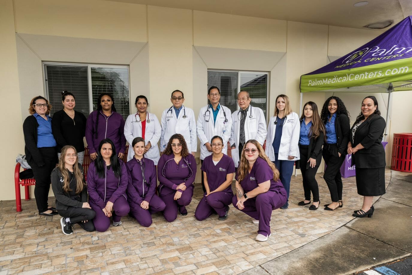 A medical team standing in front of their office building.