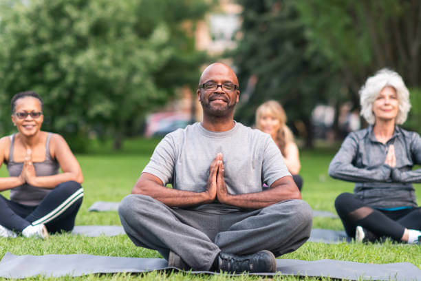 senior doing yoga at the park - healthy aging concept