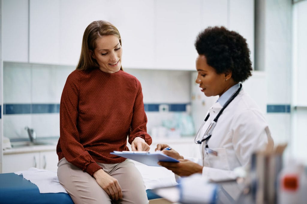 Happy woman going through her medical data with black female doctor at women's health care service medical center