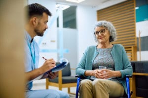 Senior woman talking to male nurse in waiting room at doctor's office