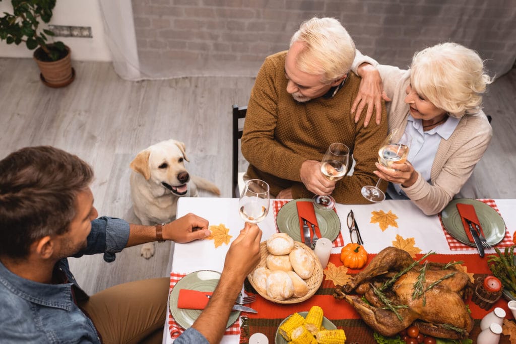 family holding glasses of white wine during thanksgiving dinner