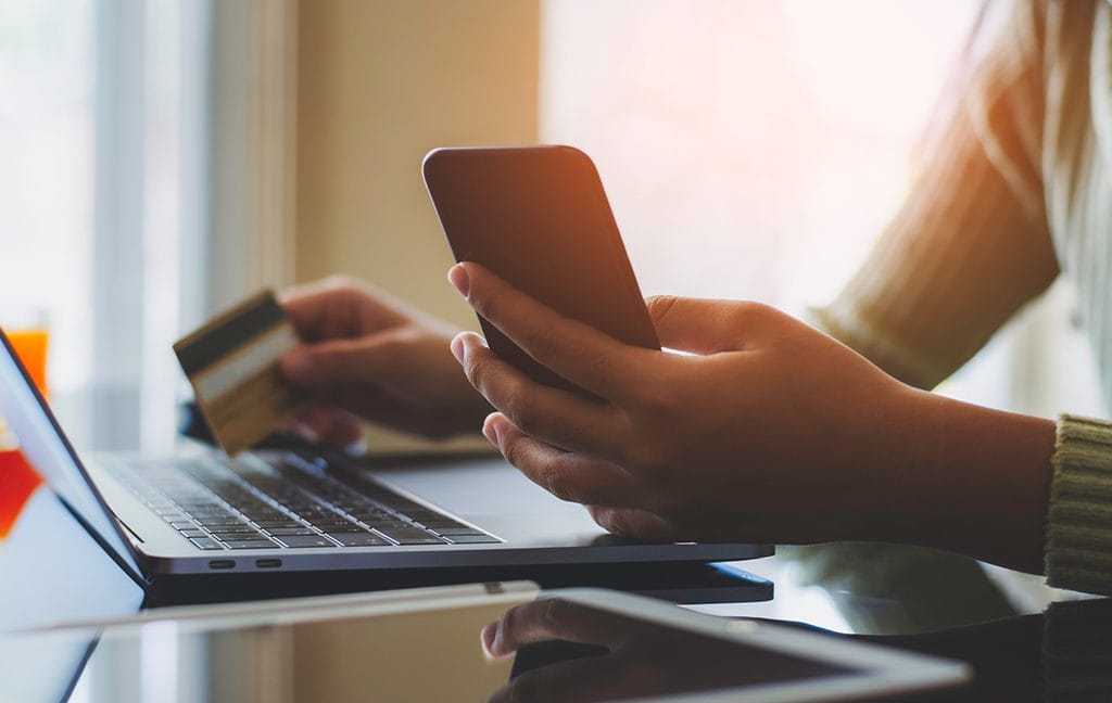 A patient getting ready to pay bills online now using his phone, laptop, and credit card.