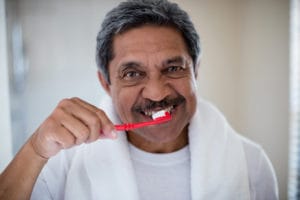 senior man brushing teeth in bathroom