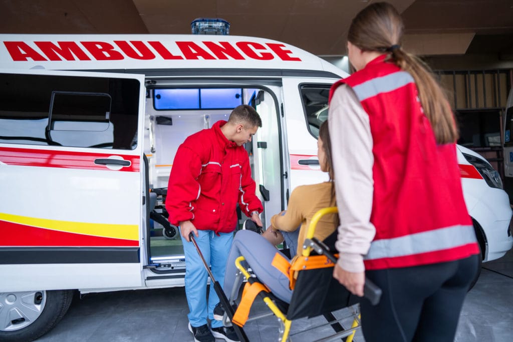 A medical emergency team is assisting a young woman who has injured her leg.