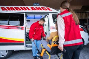 A medical emergency team is assisting a young woman who has injured her leg.