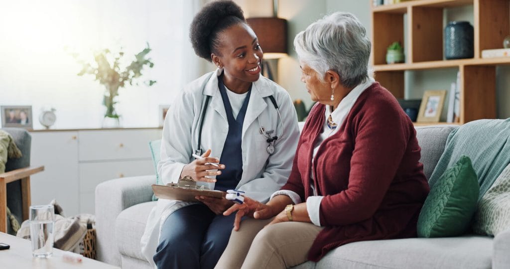 A Black female geriatric doctor is holding a medical paper document while she provides health consultation to a mature patient.