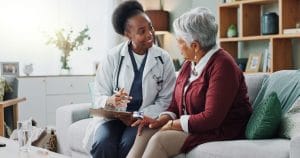 A Black female geriatric doctor is holding a medical paper document while she provides health consultation to a mature patient.