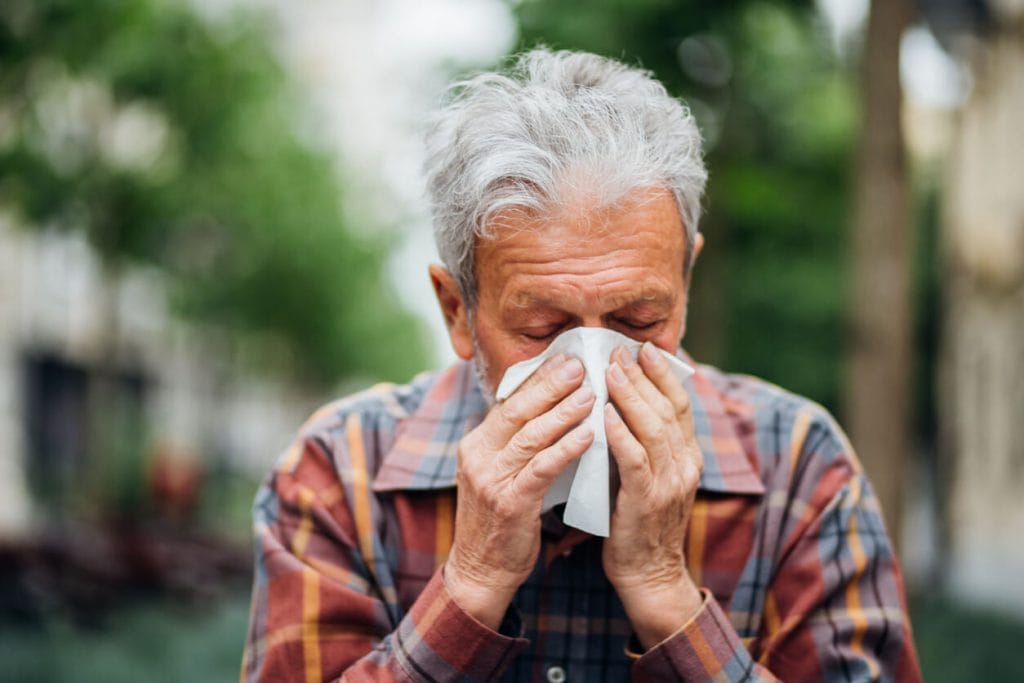 A senior man is suffering from a cold and illness due to pneumonia.