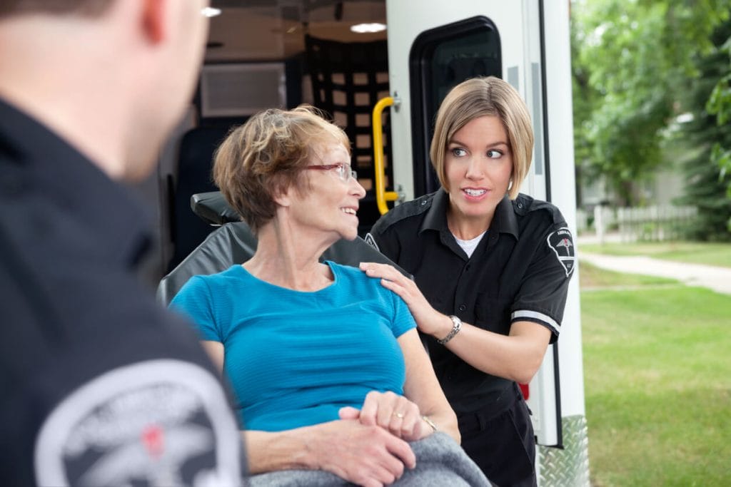 A female healthcare provider is offering medical transportation services to a senior female patient.